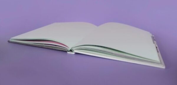 An open book with blank pages on a purple background, perfect for educational and minimalist themes.